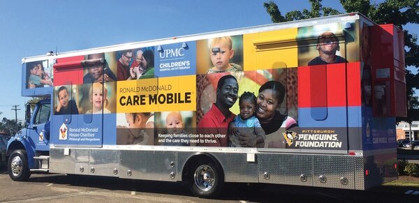 A Ronald McDonald Care Mobile truck featuring UPMC Children's Hospital and Pittsburgh Penguins Foundation logos, with photos of children and families on its exterior, highlights the importance of continuity of care in local communities.