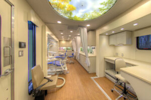 Modern mobile health clinic interior with dental chairs, equipment, workstations, and a ceiling light featuring a sky and tree design.