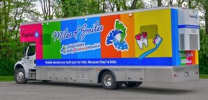 A brightly colored mobile dental care truck labeled
