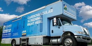 Light blue St. Elizabeth Healthcare mobile cardiovascular screening truck, similar in design to mobile audiology clinics.